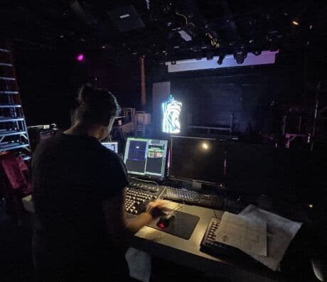 Lighting designing running a console. In front of the console desk is a mannequin being lit by Elation Fuze Max Spot fixtures.